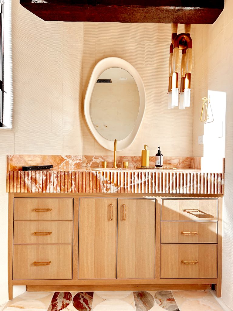 Warm desert modern bathroom with plaster walls, natural stone, and brass fixtures.